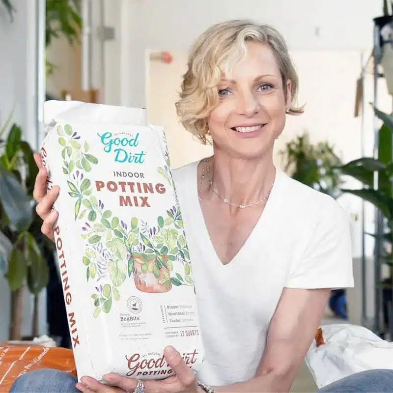 Image of plant shop owner holding a bag of highest quality potting soil in New York City